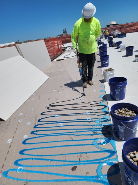 Insulation board set into ribbons of adhesive before the membrane goes down.