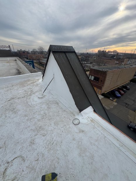 Snow at the transition between a mansard and the low-slope field behind it — where a mid-Atlantic roof leaks first.