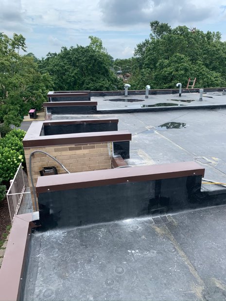 Modified bitumen field behind a brick parapet with metal coping.