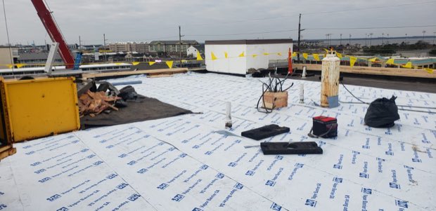 Base sheet laid out across the deck ahead of the cap sheet.