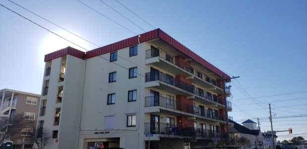 Residential building elevation with balcony stacks, roof work above.