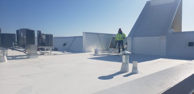 Crew crossing a reflective roof between mechanical units.