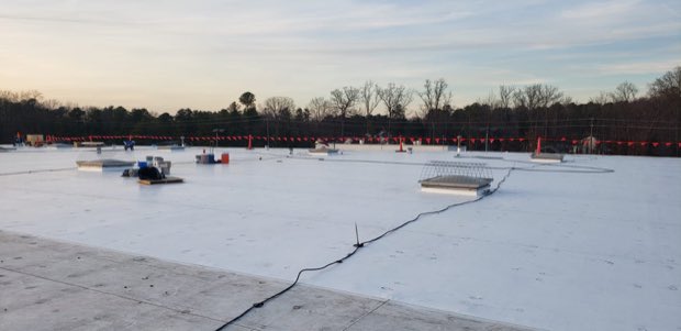 Dusk over a flat roof with mechanical curbs in silhouette.