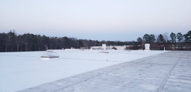 Snow covering a flat commercial roof after a winter storm.