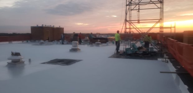 Crew working at sunrise behind perimeter safety netting.