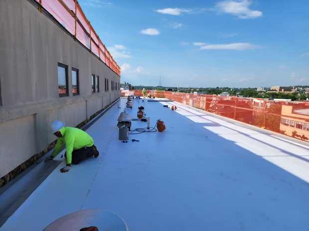 Crew detailing a seam on a partially completed roof.