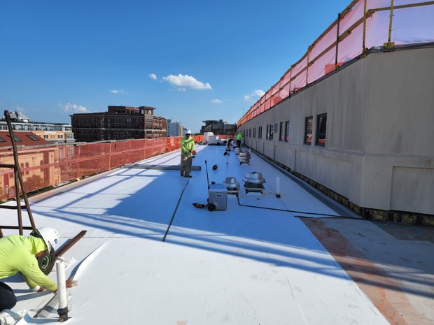 Ladder access and staged material along a roof run.