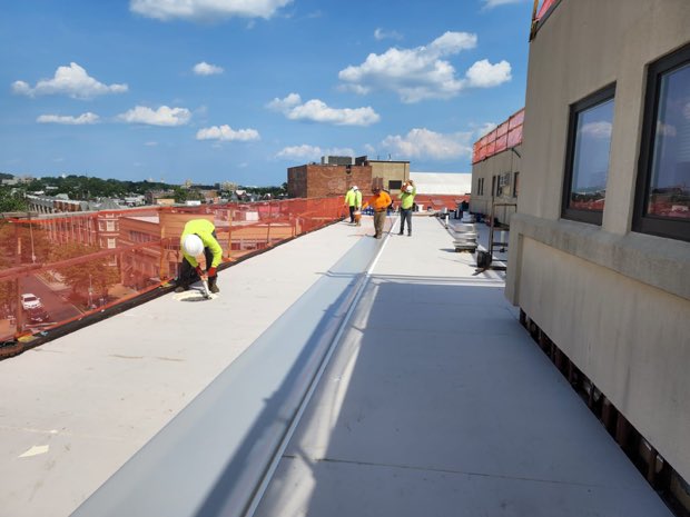 Crew working alongside a rooftop penthouse wall.