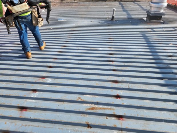 Worker crossing an exposed corrugated metal deck.