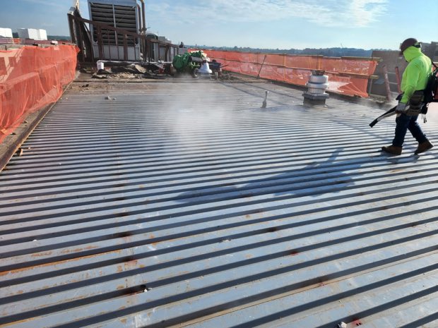 Priming a corrugated metal deck ahead of the new assembly.