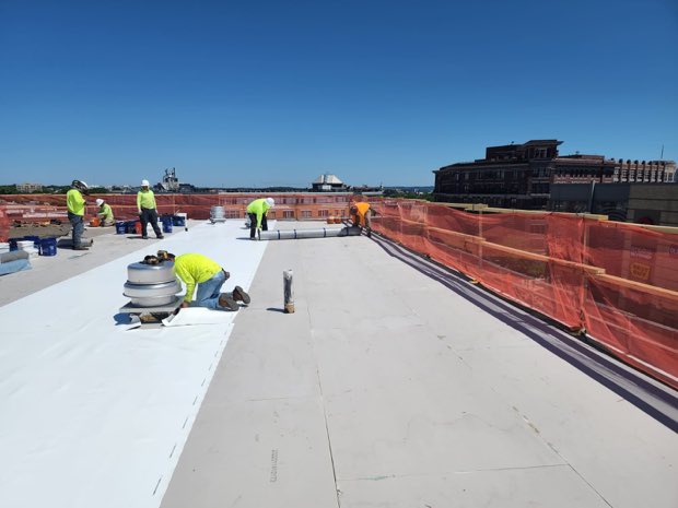 Crew and staged material on an open roof section.