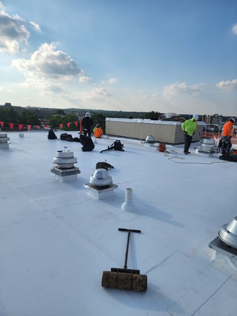 Crew working around rooftop vents on a completed section.