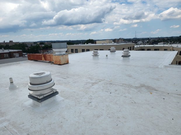 Completed white roof, masonry building and city beyond.