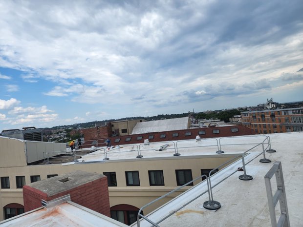 Completed roof under heavy cloud, city beyond.