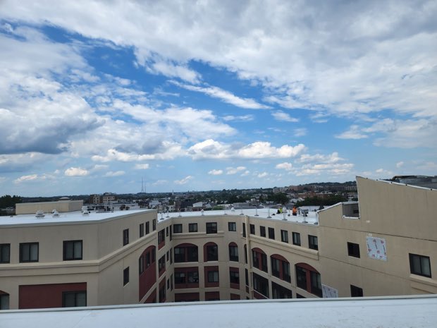 Finished roof under cloud, masonry parapet in the foreground.