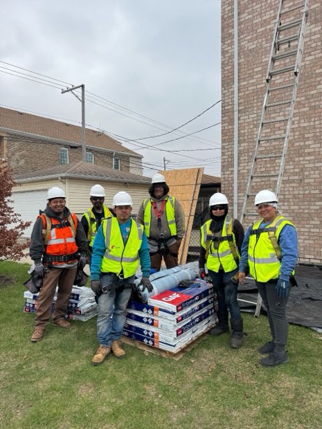 Crew and staged material at a stucco building before the tear-off starts.