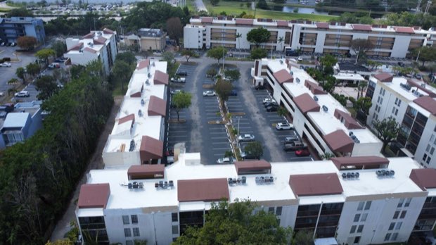 Low-rise apartment blocks with tile and reflective roof sections.