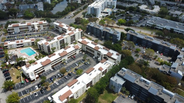 Aerial across a multi-building residential property with a central pool deck.