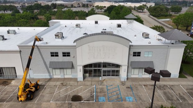 Large civic building with a lift on site during roof work.