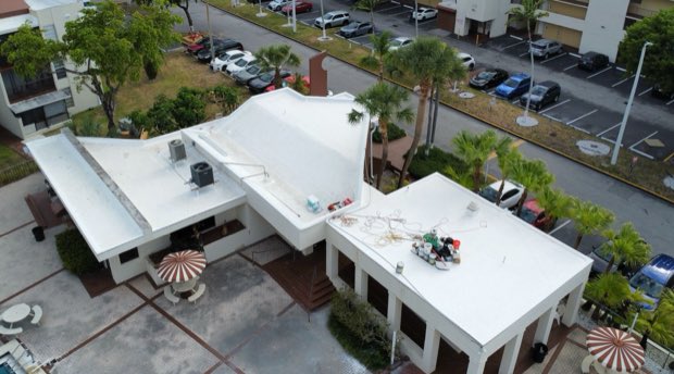 Reflective roofs on a mid-century commercial building, parking field beyond.