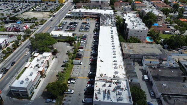 Aerial along a corridor showing a long run of completed roofing.