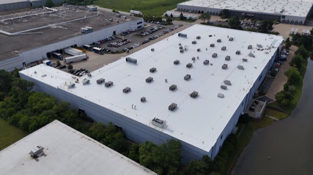 Warehouse property from above, trailers on the dock and completed roof across the span.
