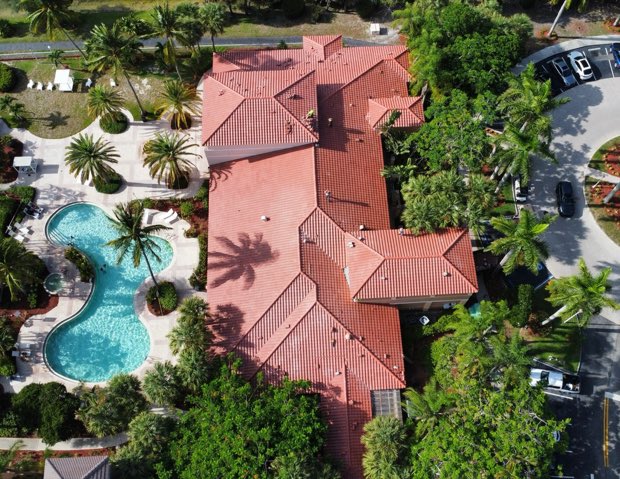 Barrel tile roofs around a pool deck, dense tropical planting throughout.