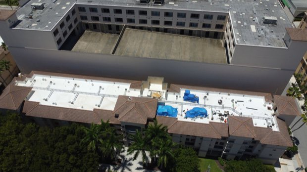 Reflective roof on a mid-rise concrete building, parapet and edge metal visible.