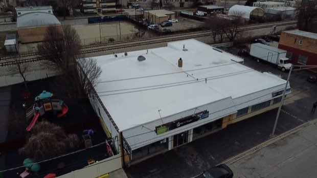 Completed reflective roof over a retail building, palms at the perimeter.